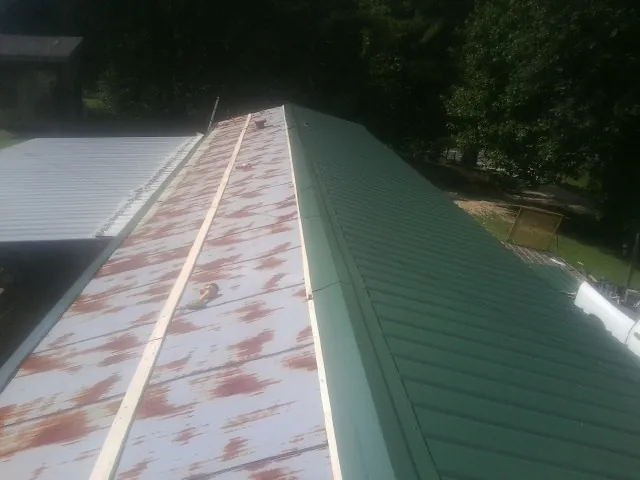 Old rusted panels beside newly installed green metal roofing — Wind Damage Roof Repair by Roofing Brothers in Ballwin