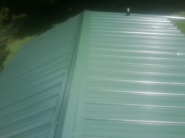 New green metal panels meeting at the ridge of a roof — Flat Roof Repair work by our crew in Ballwin