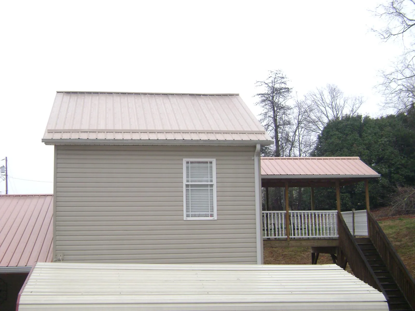 Tan metal roofs on a two story addition and attached porch, from a Roof Replacement job in Ballwin
