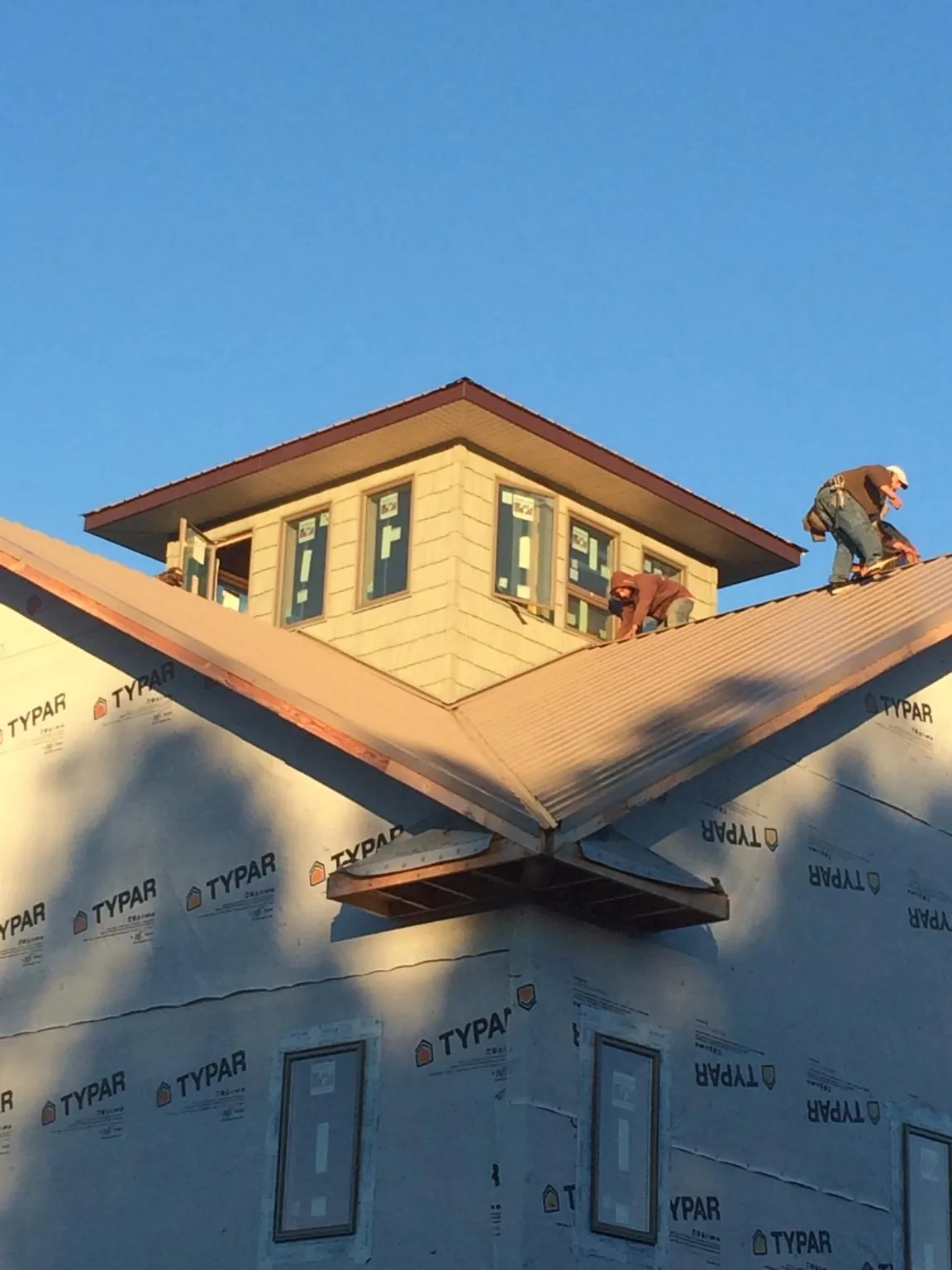 Roofers working around a rooftop cupola on a new metal roof at sunset — Roof Waterproofing in Ballwin by Roofing Brothers
